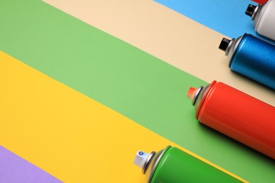 Photo of Cans of different spray paints on color background, space for text. Graffiti supplies