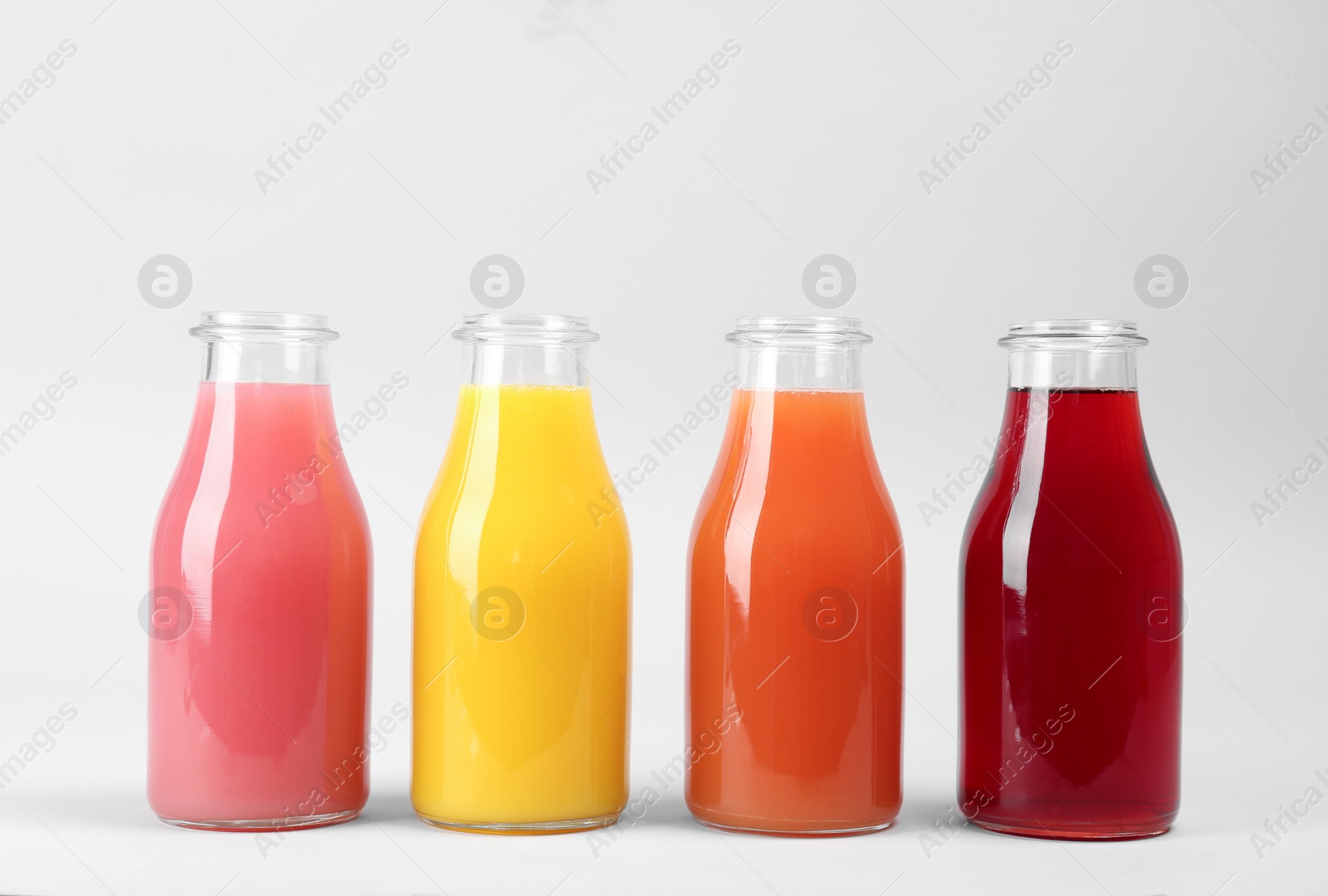 Photo of Bottles with delicious colorful juices on light background