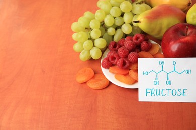 Photo of Card with word Fructose, delicious ripe fruits, raspberries and dried apricots on wooden table, space for text