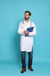 Photo of Full length portrait of doctor with stethoscope and clipboard on light blue background