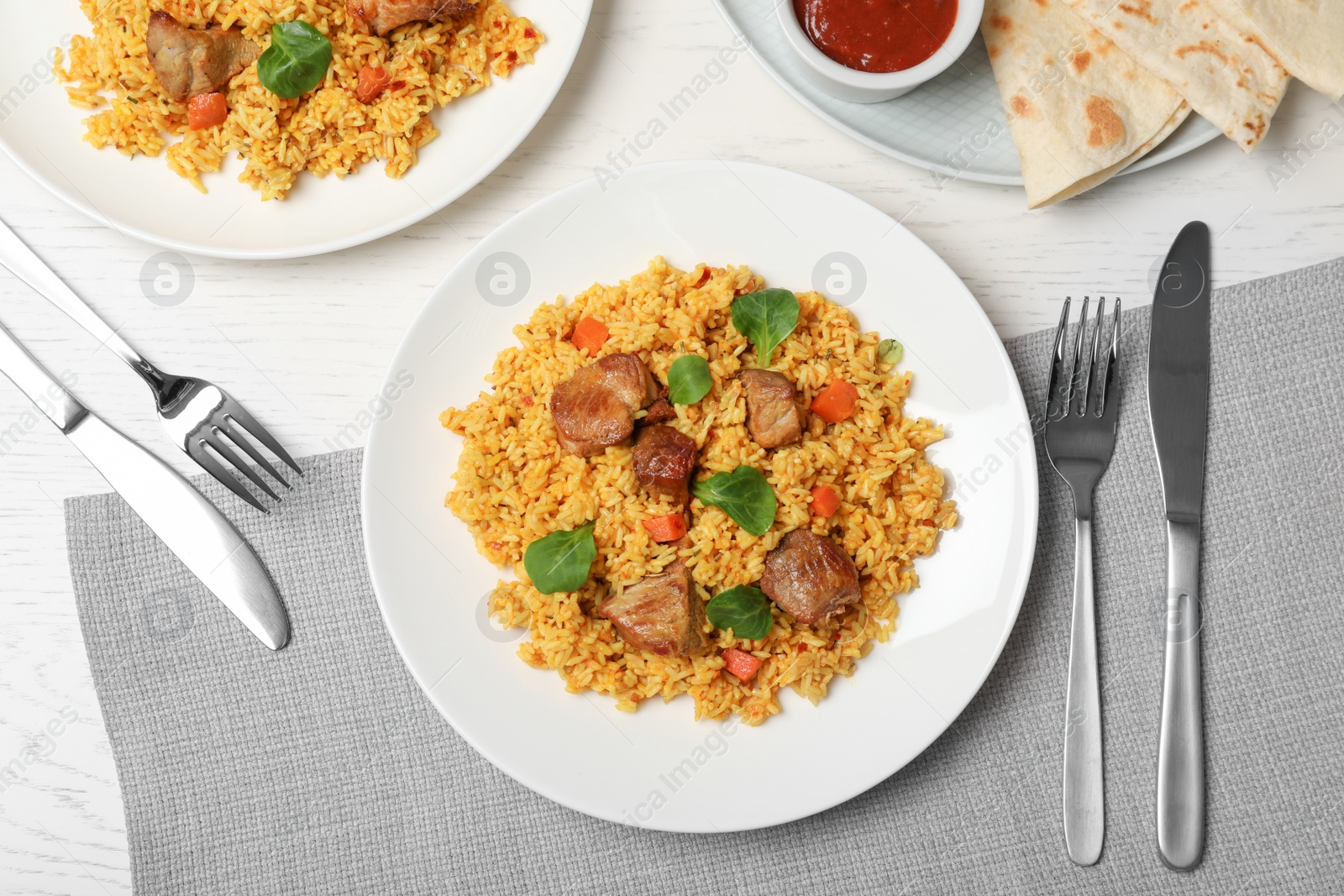 Photo of Plate of delicious rice pilaf served on light table, flat lay