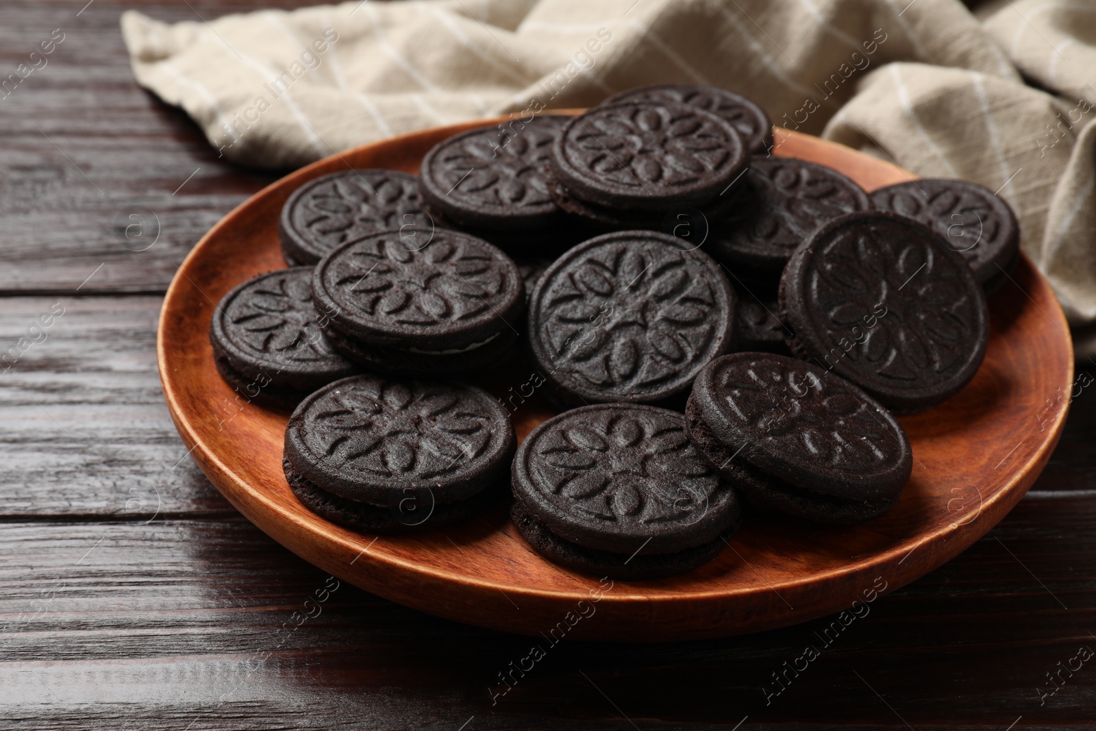 Photo of Plate with tasty sandwich cookies on wooden table, closeup