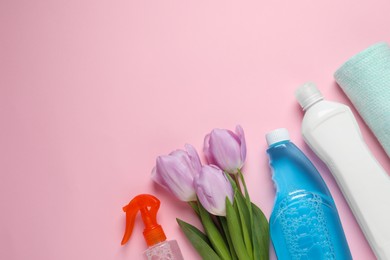Spring cleaning. Detergents, flowers and rag on pink background, flat lay. Space for text
