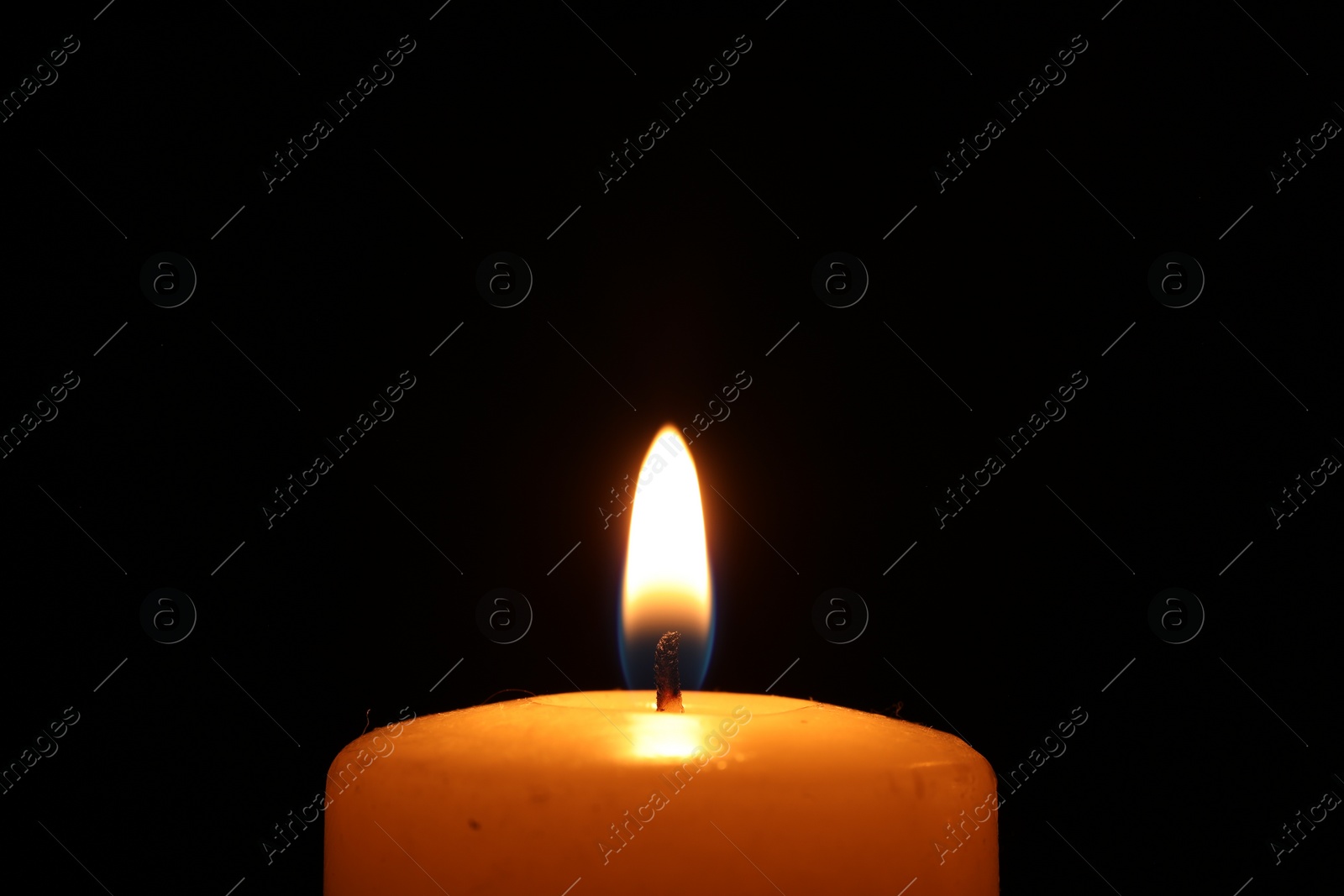 Photo of Burning wax candle on black background, closeup