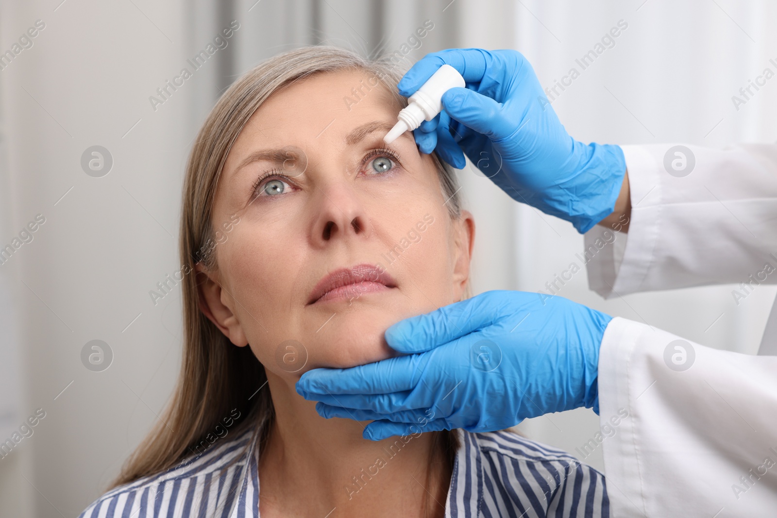 Photo of Medical drops. Doctor dripping medication into woman's eye indoors