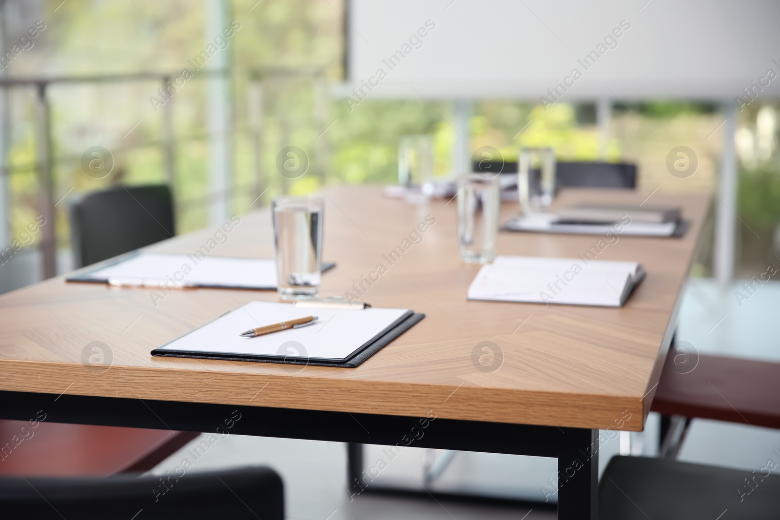 Photo of Clipboards and glasses of water on wooden table in modern office