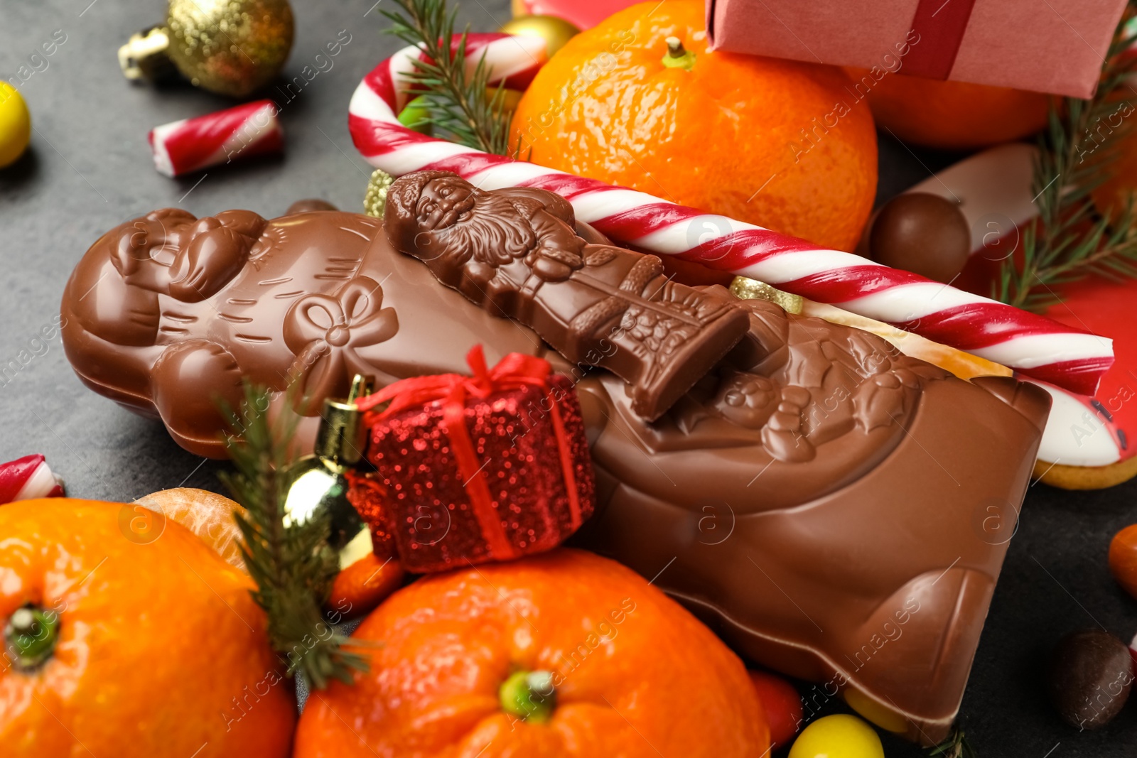 Photo of Chocolate Santa Claus candies and tangerine fruits, closeup