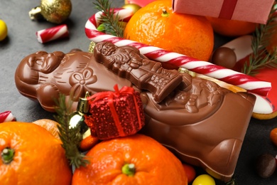 Photo of Chocolate Santa Claus candies and tangerine fruits, closeup