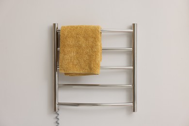 Photo of Heated rail with yellow towel on white wall