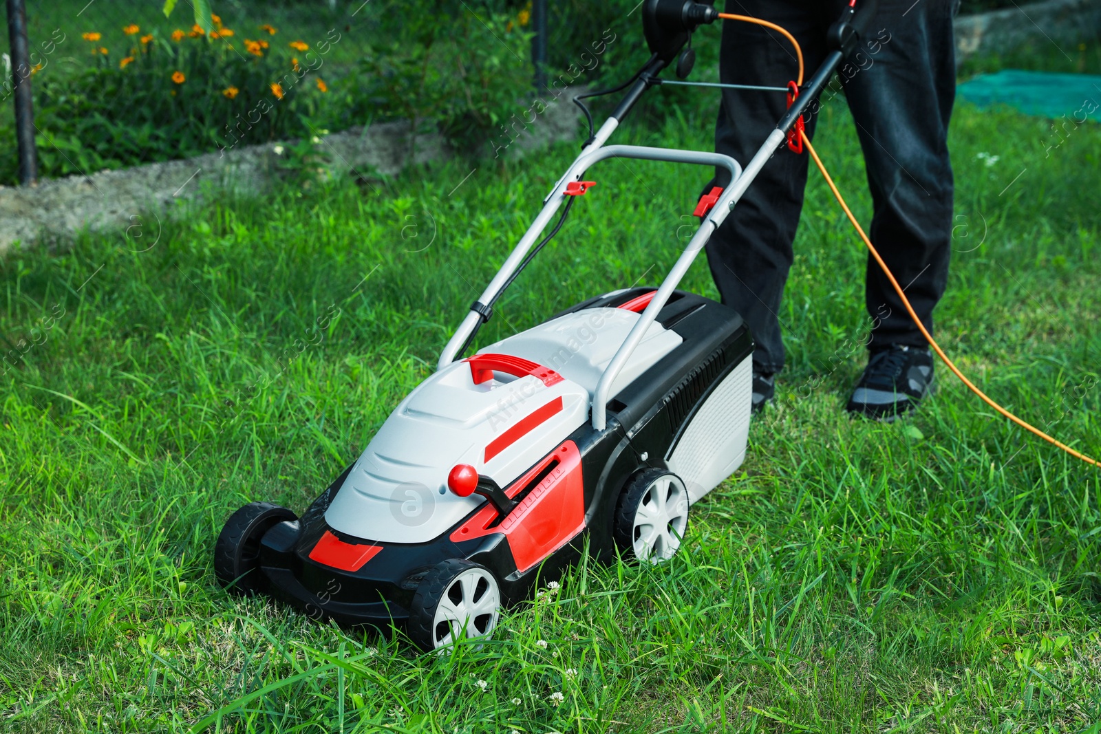 Photo of Man cutting grass with lawn mower in garden, closeup