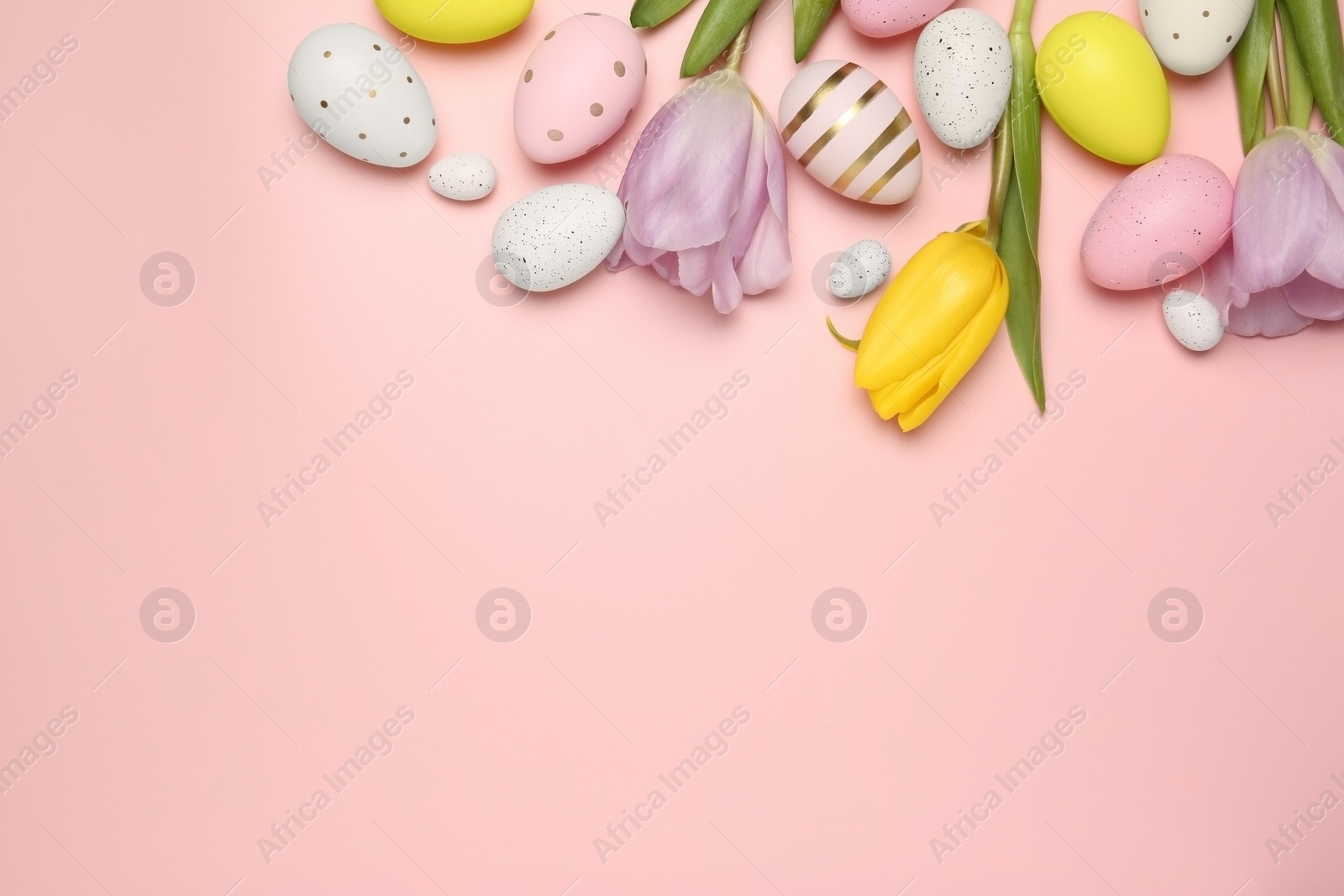 Photo of Flat lay composition with festively decorated Easter eggs and beautiful tulips on pink background. Space for text