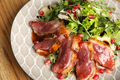 Photo of Delicious salad with roasted duck breast served on wooden table, closeup