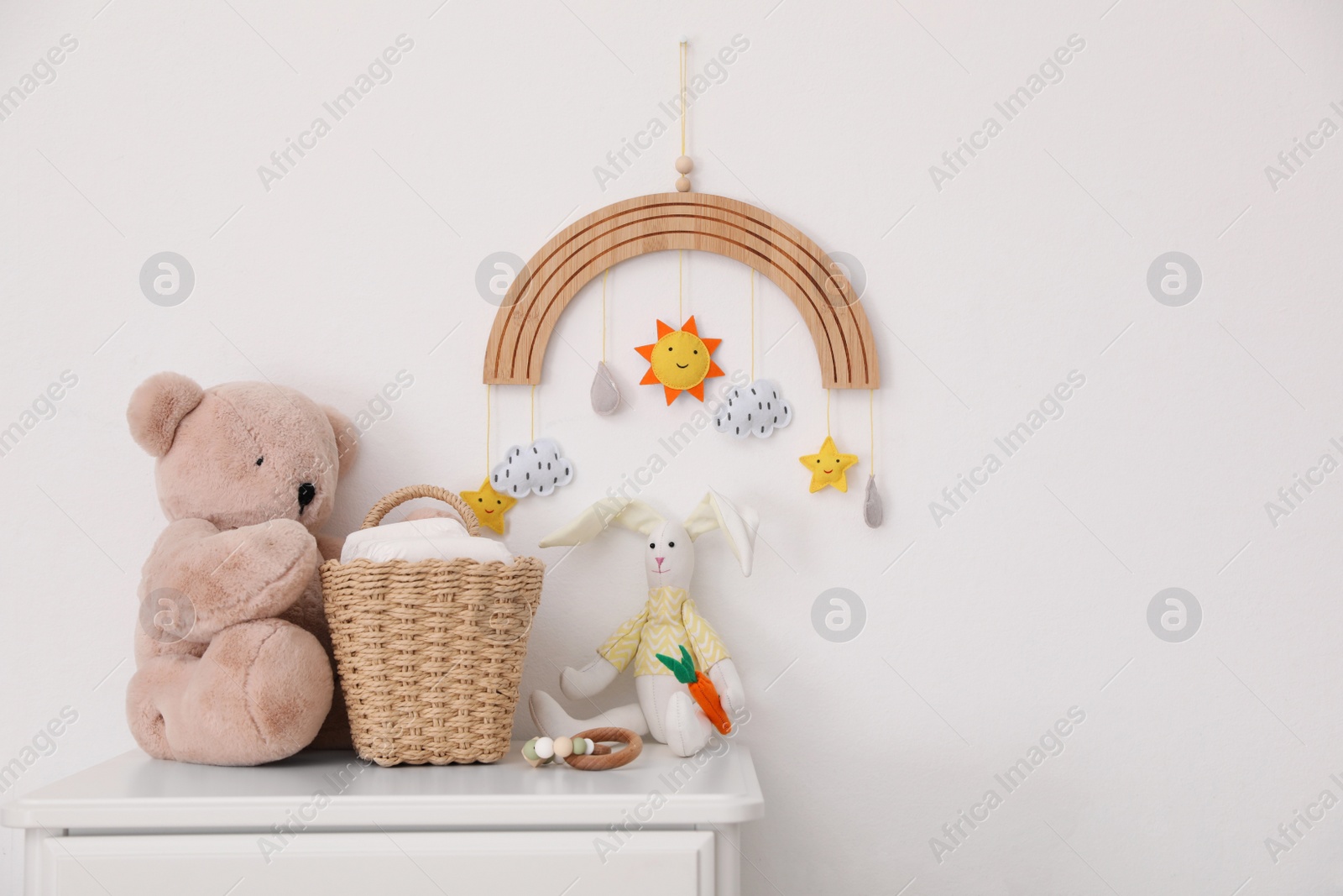 Photo of Commode with toys and diapers near light wall in baby room. Interior design