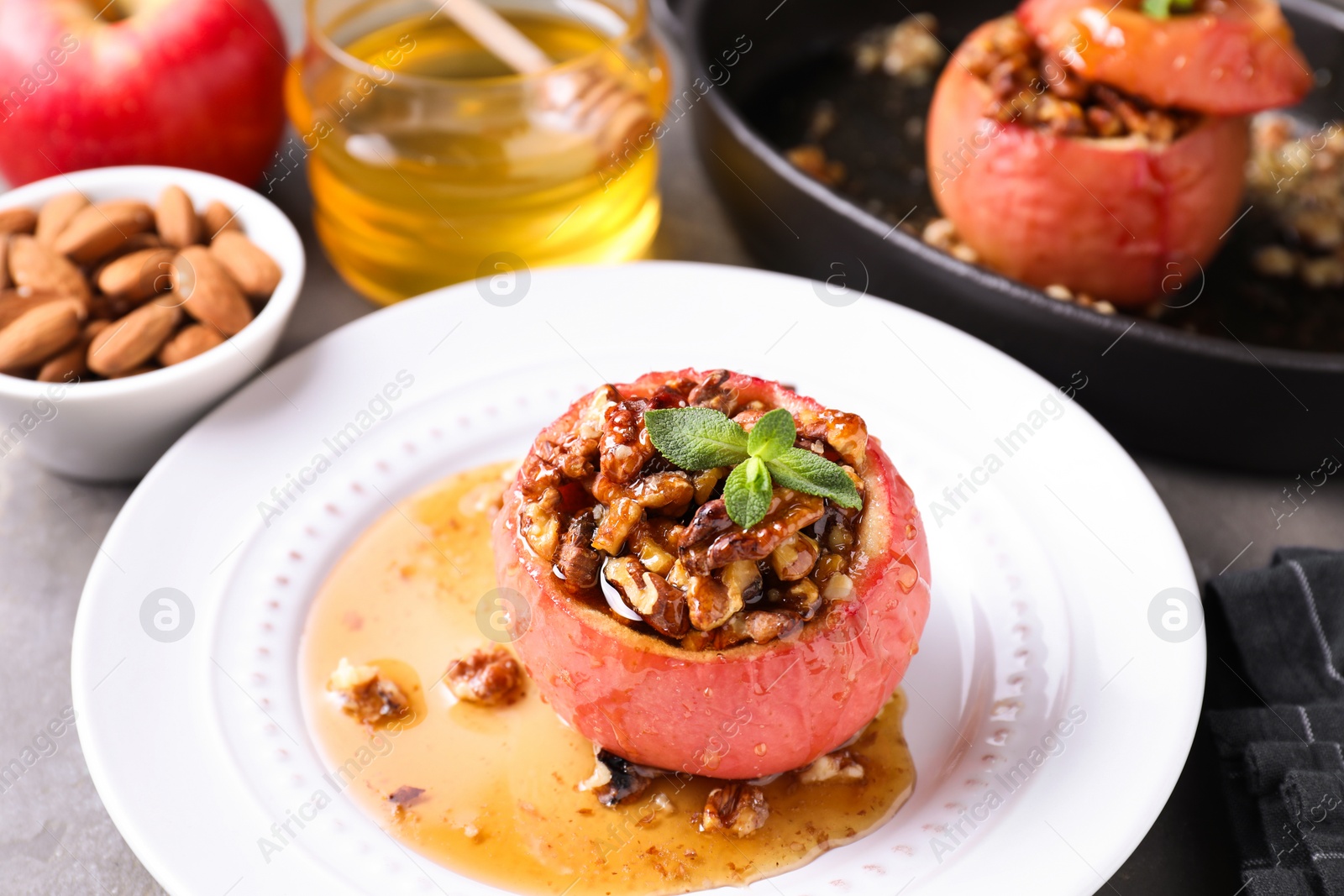 Photo of Tasty baked apple with nuts, honey and mint on table, closeup