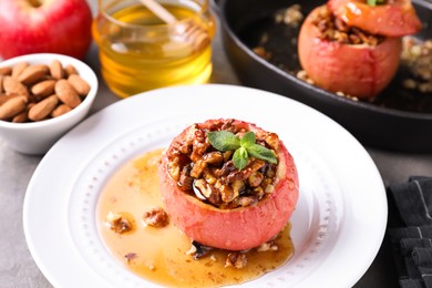 Photo of Tasty baked apple with nuts, honey and mint on table, closeup