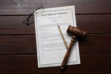 Photo of Last Will and Testament with glasses, gavel and pen on wooden table, flat lay