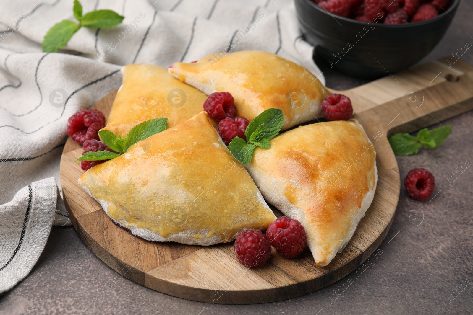 Photo of Delicious samosas with raspberries on grey table, closeup