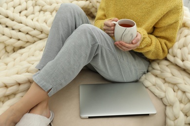Photo of Woman with cup of tea and laptop sitting on sofa, closeup