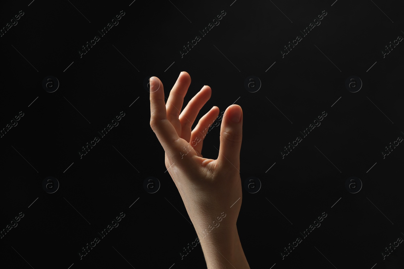 Photo of Woman holding something in hand on black background, closeup