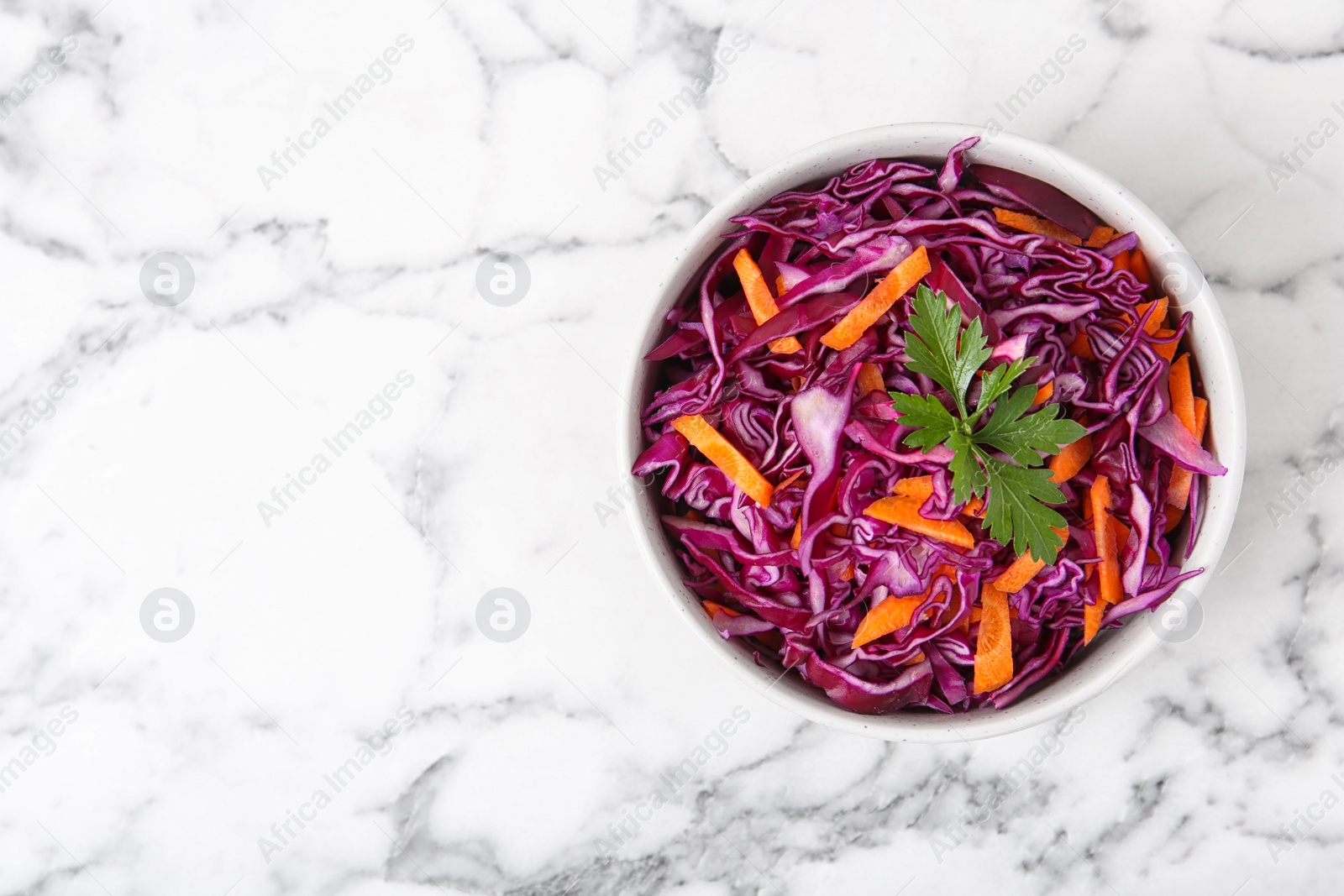 Photo of Bowl with chopped red cabbage on marble table, top view