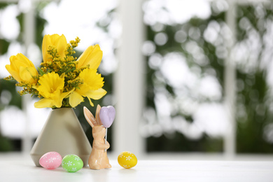 Photo of Festive composition with Easter eggs on table against blurred window, space for text