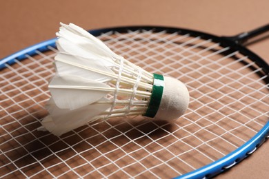 Photo of Feather badminton shuttlecock and racket on brown background, closeup