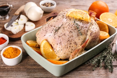 Photo of Raw chicken, orange slices and other ingredients on wooden table