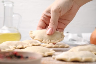 Photo of Woman making dumplings (varenyky) with tasty filling at table, closeup