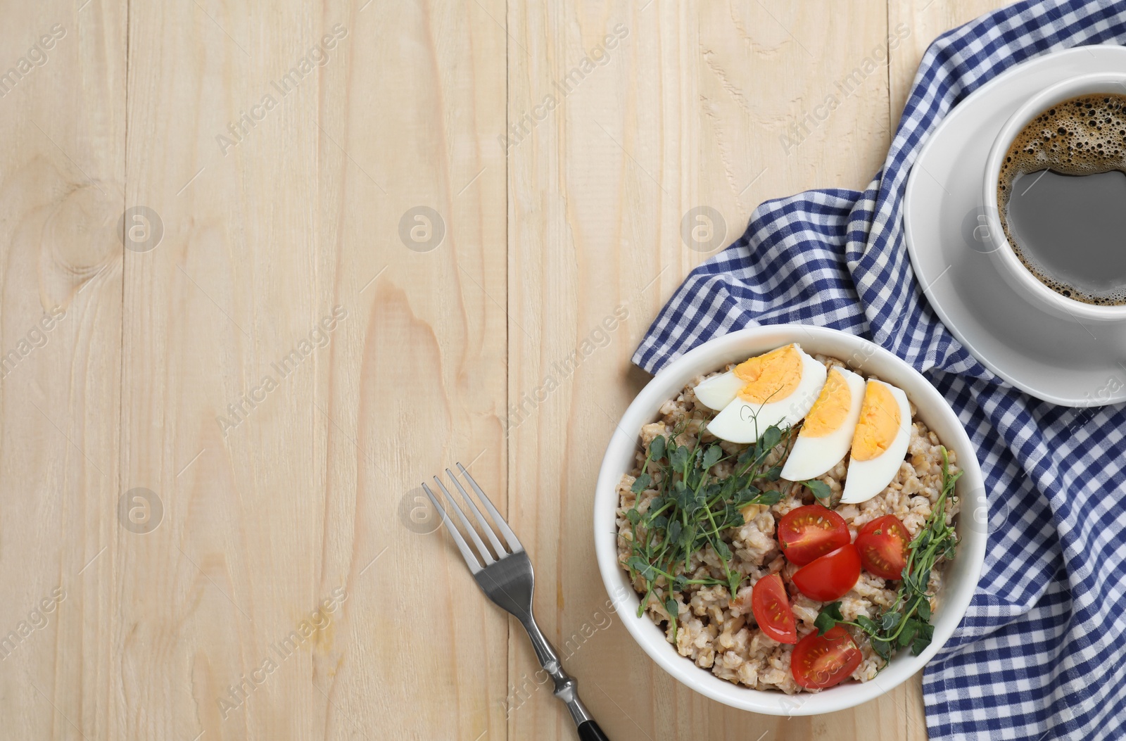 Photo of Tasty boiled oatmeal with egg and tomatoes served on wooden table, flat lay. Space for text
