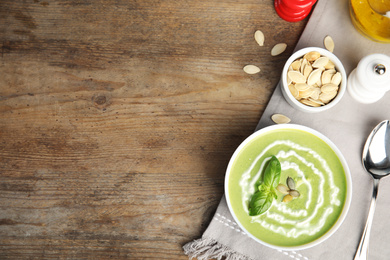 Delicious broccoli cream soup served on wooden table, flat lay. Space for text