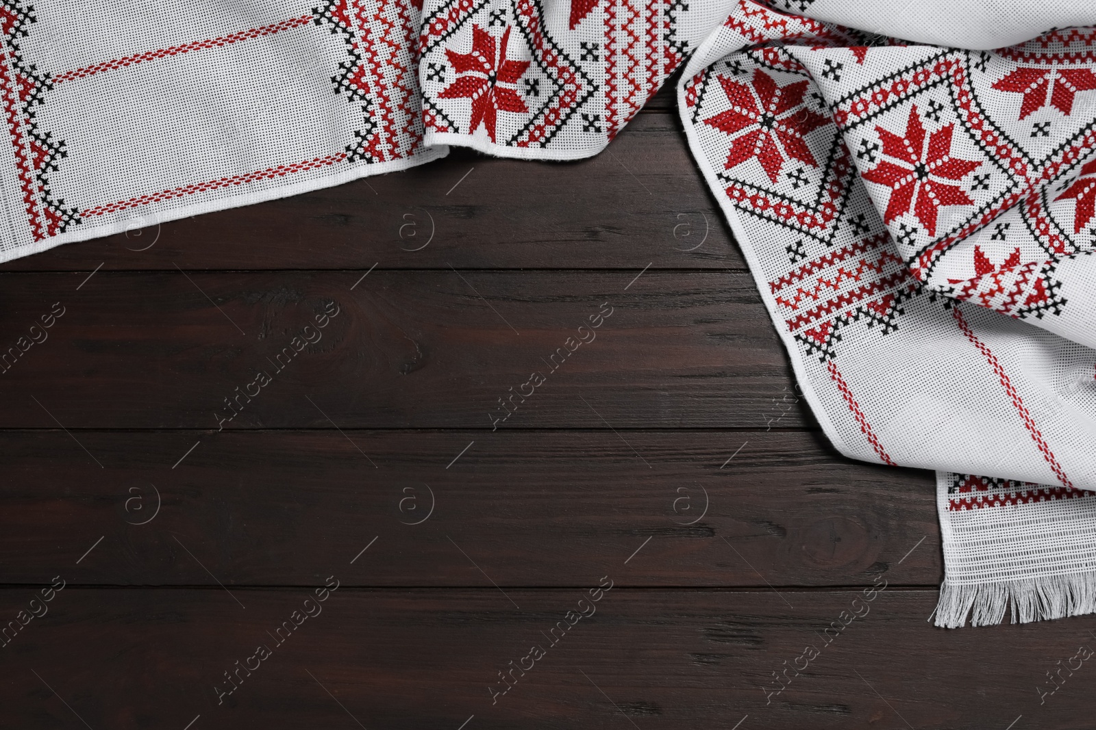 Photo of Beautiful rushnyk on wooden table, top view with space for text. Ukrainian national embroidery