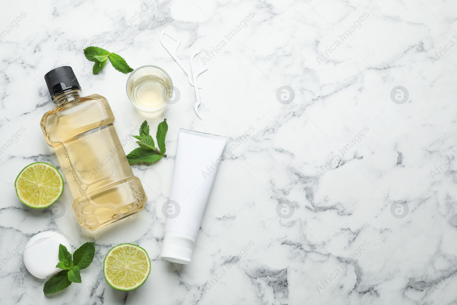 Photo of Flat lay composition with mouthwash and other oral hygiene products on white marble table. Space for text