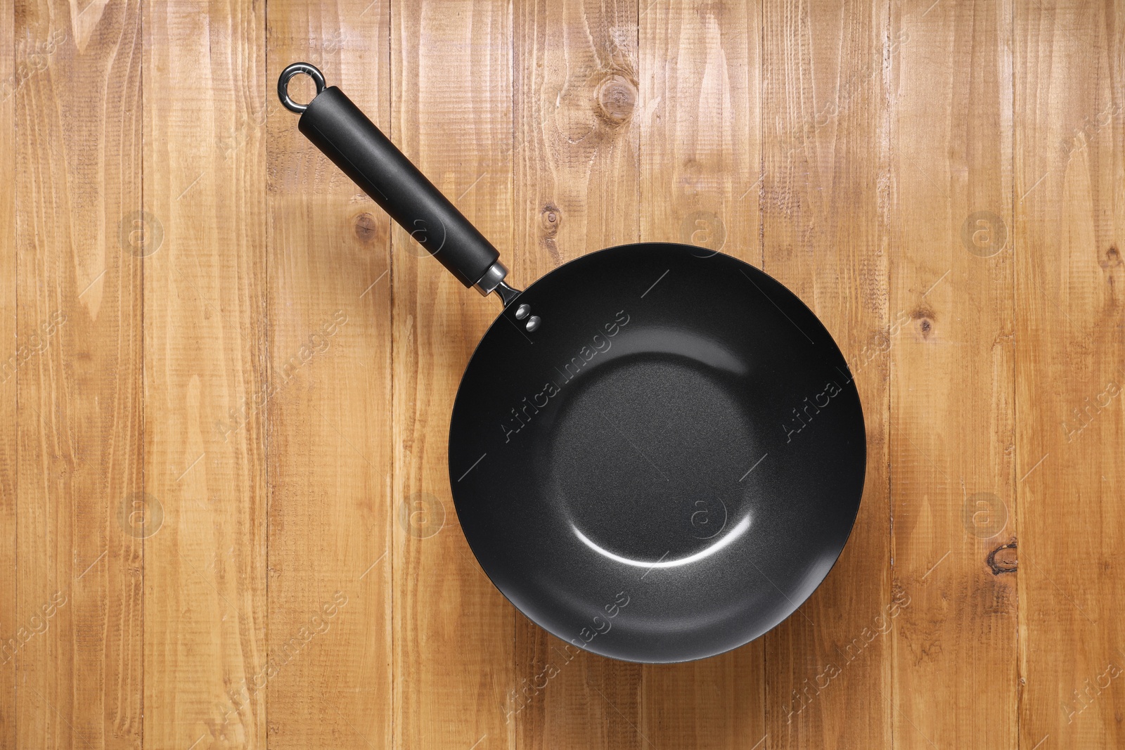 Photo of Empty iron wok on wooden table top view. Chinese cookware