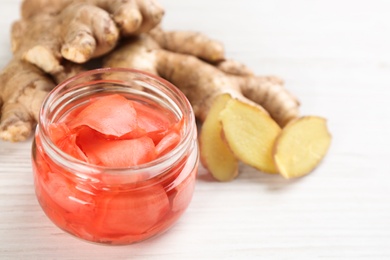 Spicy pickled ginger and root on white wooden table, space for text