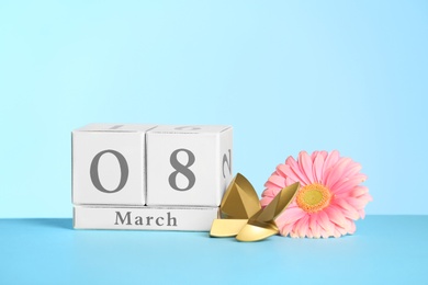 Photo of Composition with calendar and flower on table against color background, space for text International Women's Day