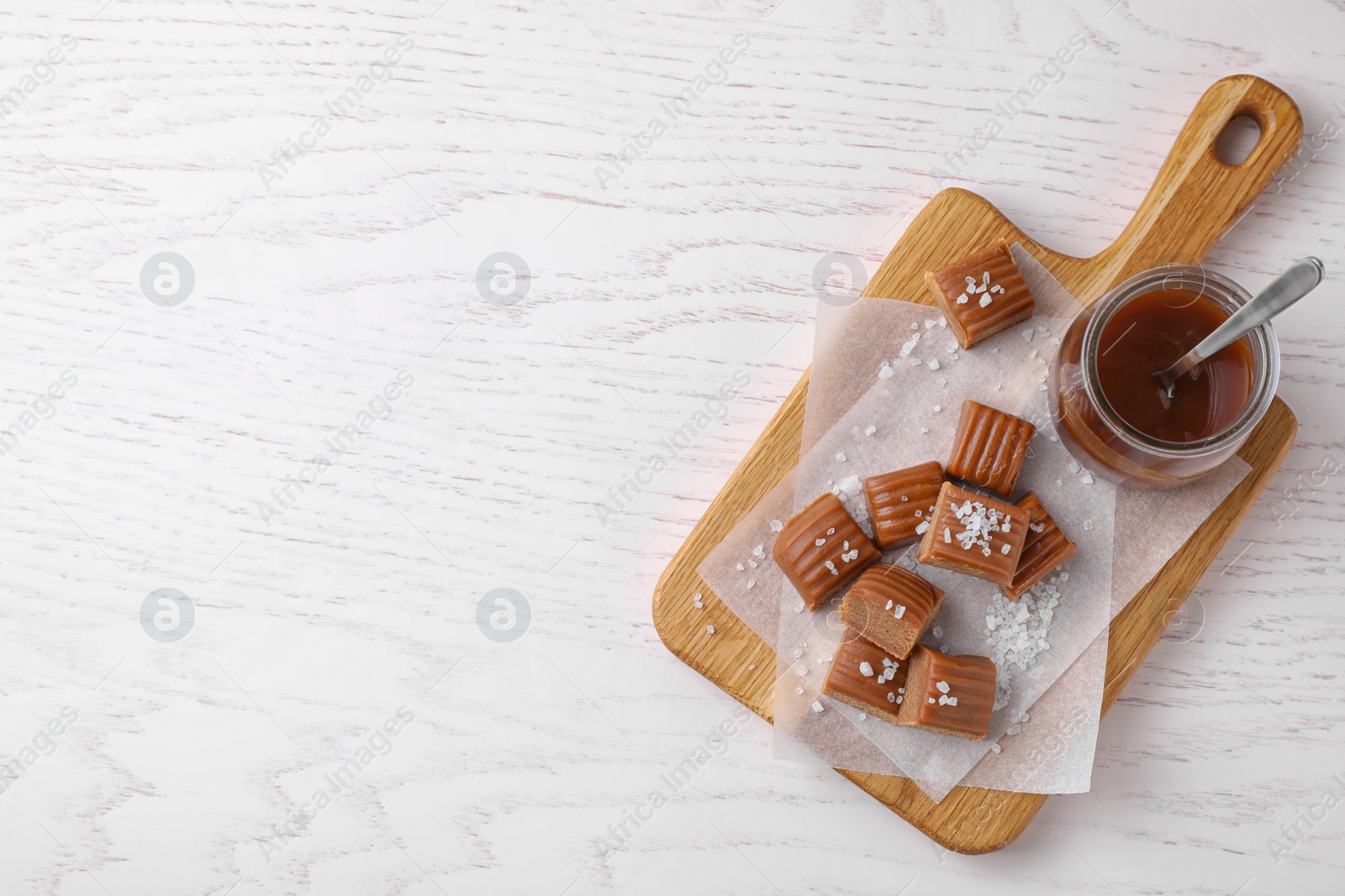 Photo of Delicious salted caramel on white wooden table, top view. Space for text