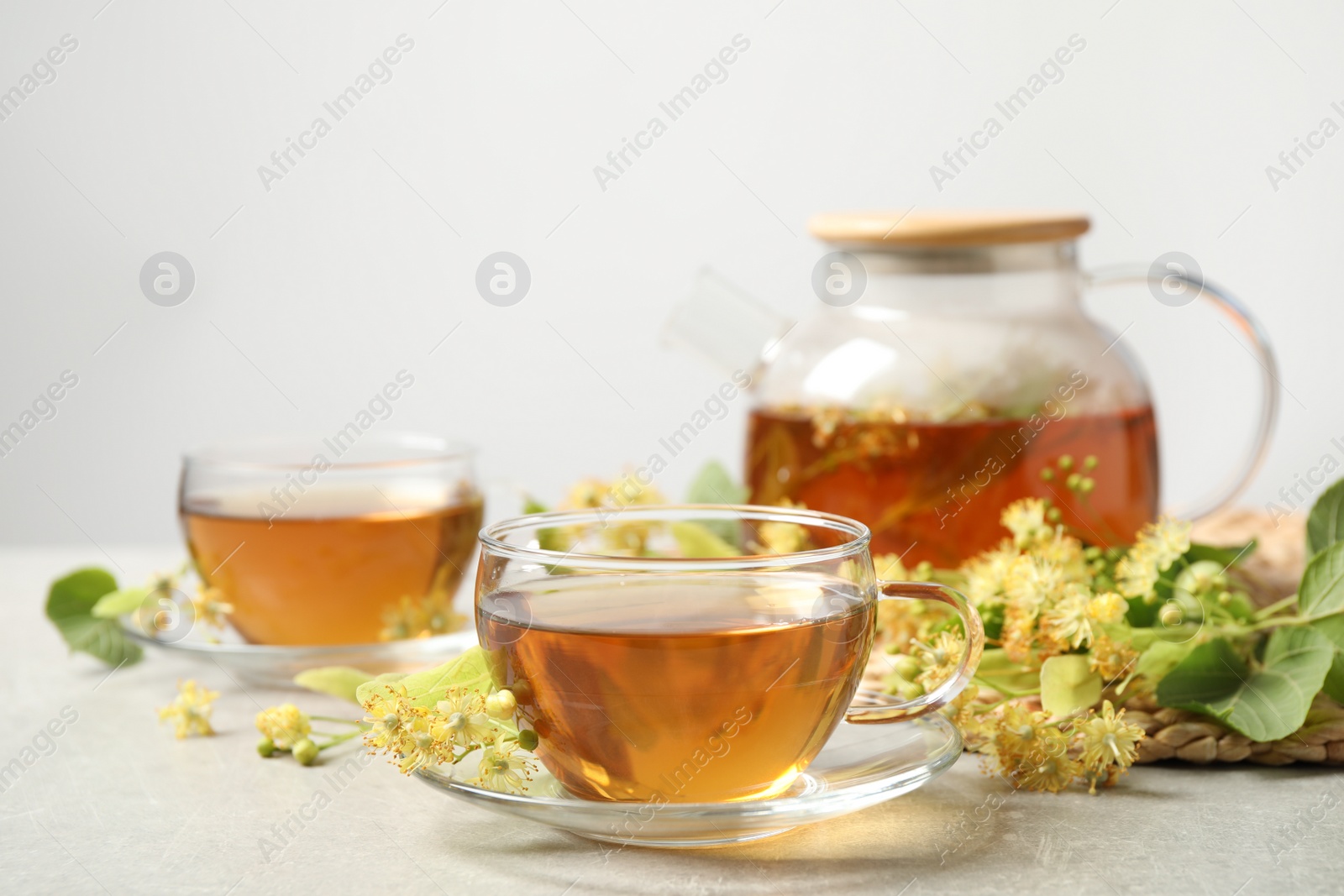 Photo of Tasty tea and linden blossom on light grey table. Space for text