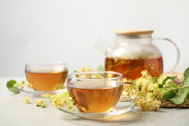 Tasty tea and linden blossom on light grey table. Space for text