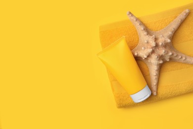 Photo of Tube of sunscreen, starfish and towel on orange background, top view with space for text. Sun protection