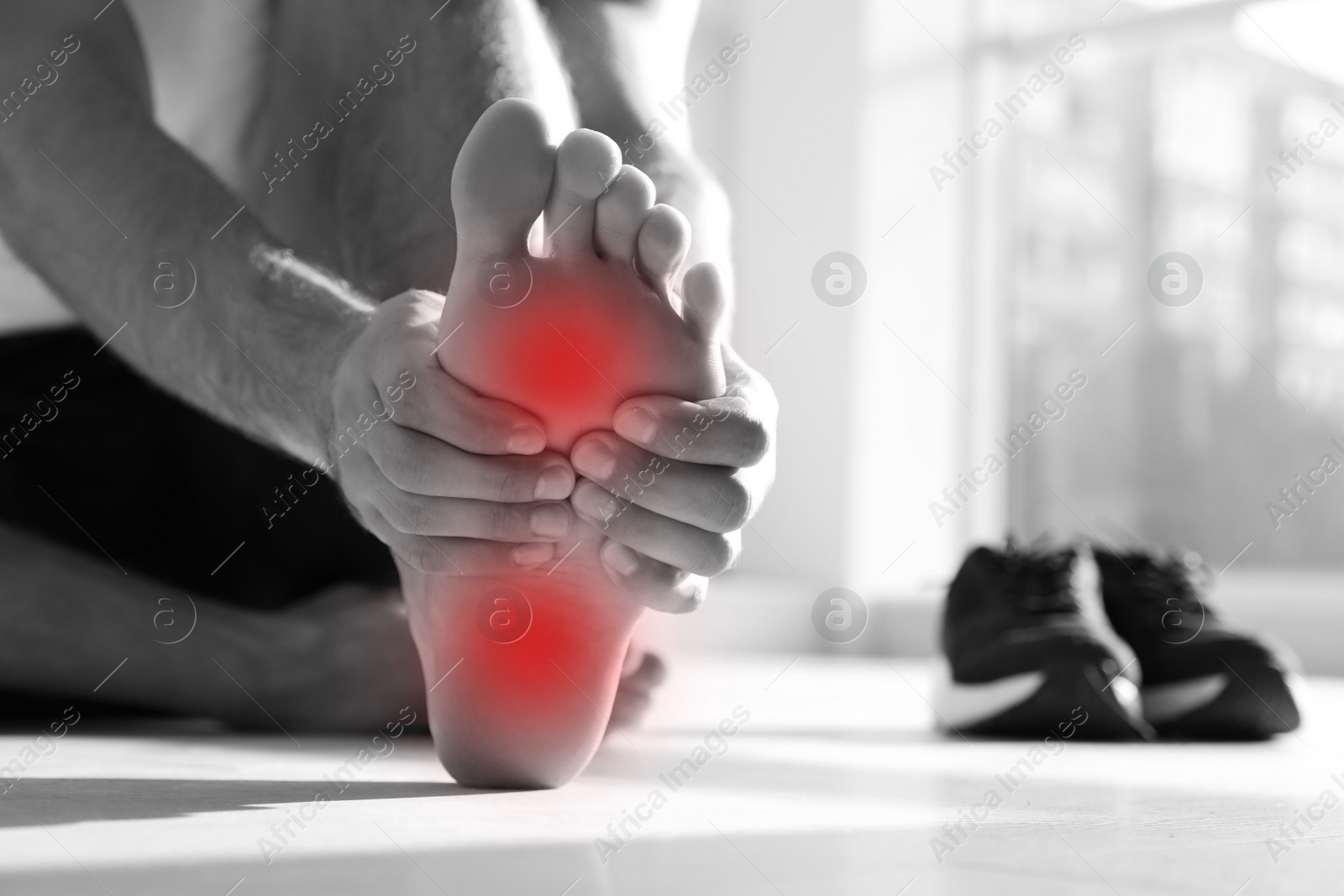 Image of Man suffering from foot pain on floor indoors, closeup