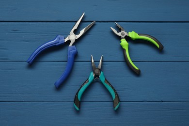 Pliers on blue wooden table, flat lay