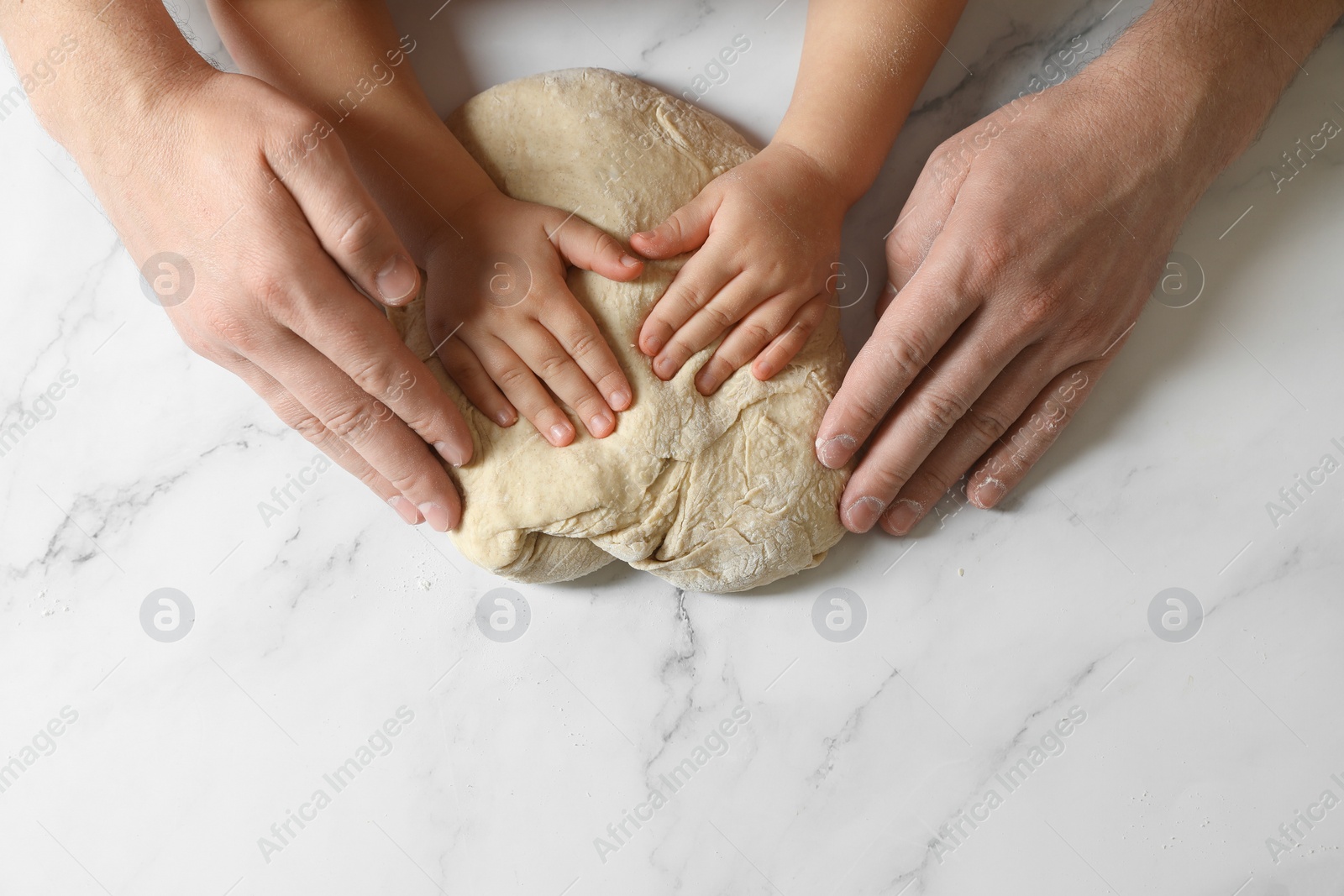Photo of Father and child making dough at white table, top view