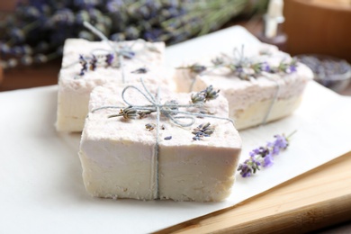 Photo of Hand made soap bars with lavender flowers on white paper, closeup
