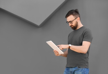 Photo of Portrait of young man with tablet near grey wall