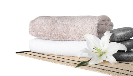 Photo of Mat with towels, flower and spa stones on white background