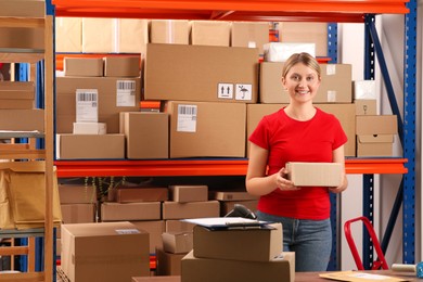 Photo of Post office worker with parcel near rack indoors