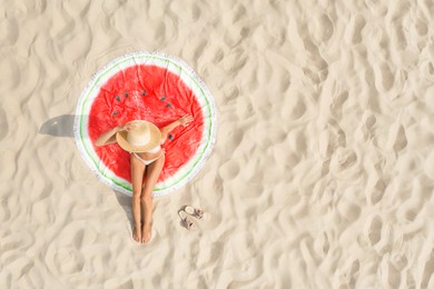 Woman sunbathing on round beach towel at sandy coast, aerial view. Space for text