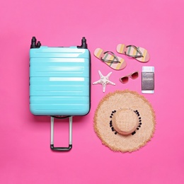 Photo of Blue suitcase and beach objects on pink background, flat lay