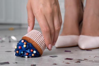 Photo of Woman picking up dropped cupcake from floor, closeup. Troubles happen