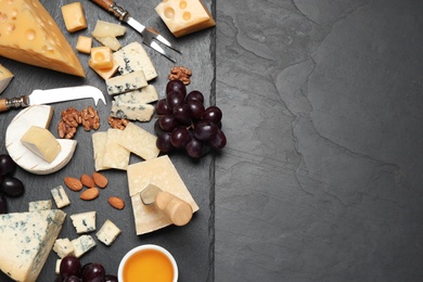 Photo of Cheese platter with specialized knife and fork on black table, flat lay .Space for text
